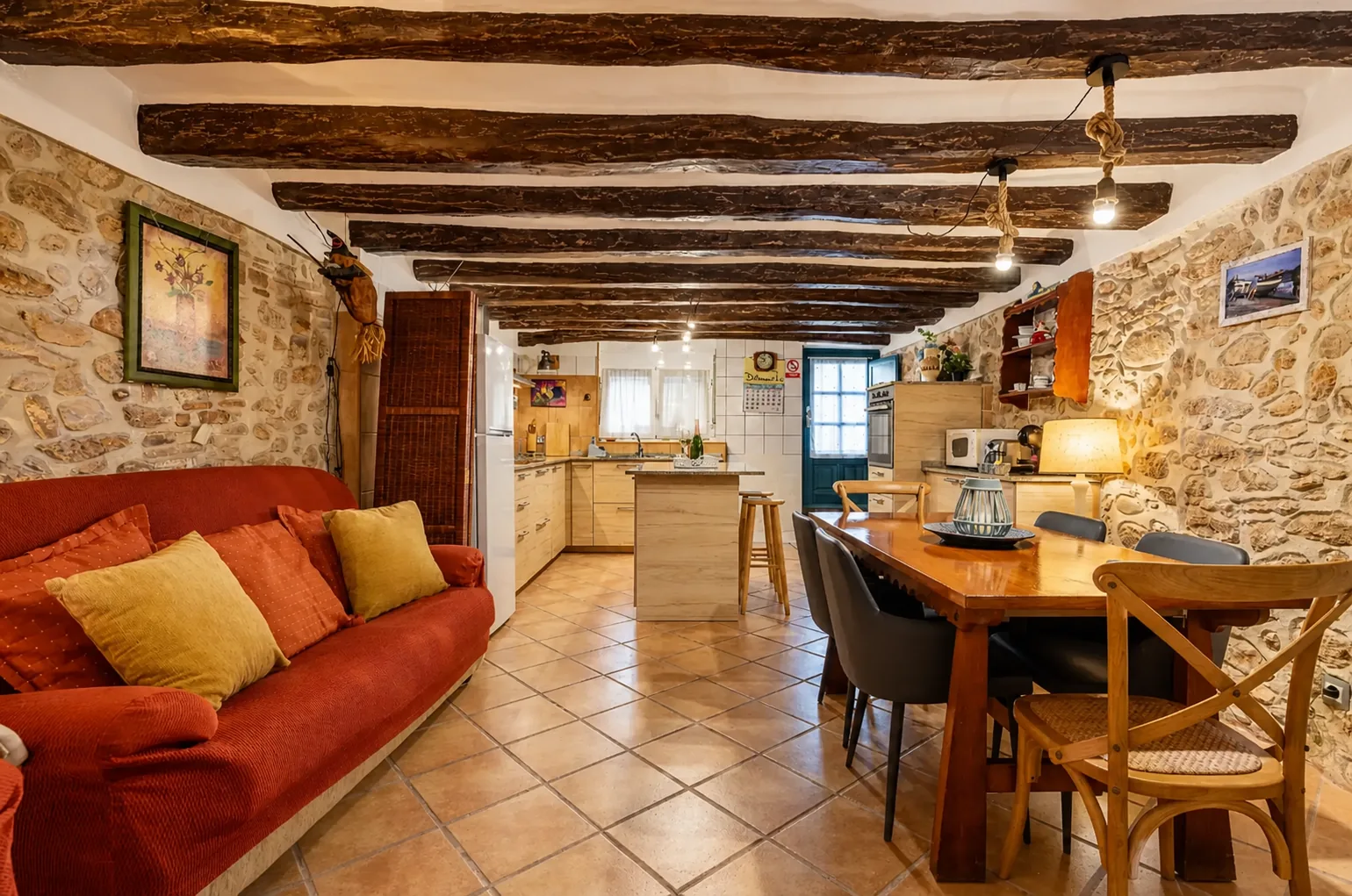 Salón de Casa Cal Cot con paredes de piedra, vigas de roble y la mesa de madera