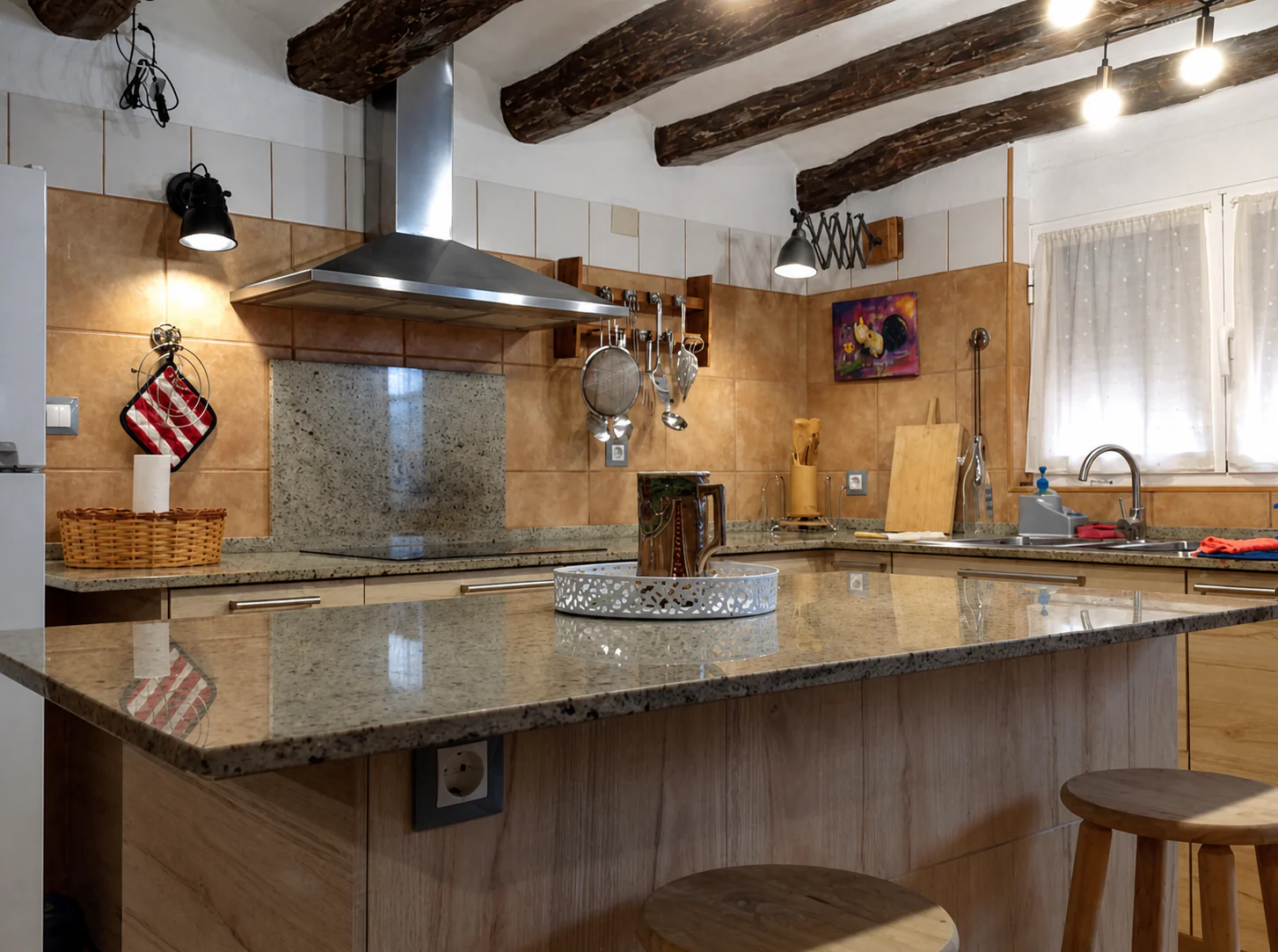 Isla de la cocina con encimera de granito, campana extractora y vigas de madera.